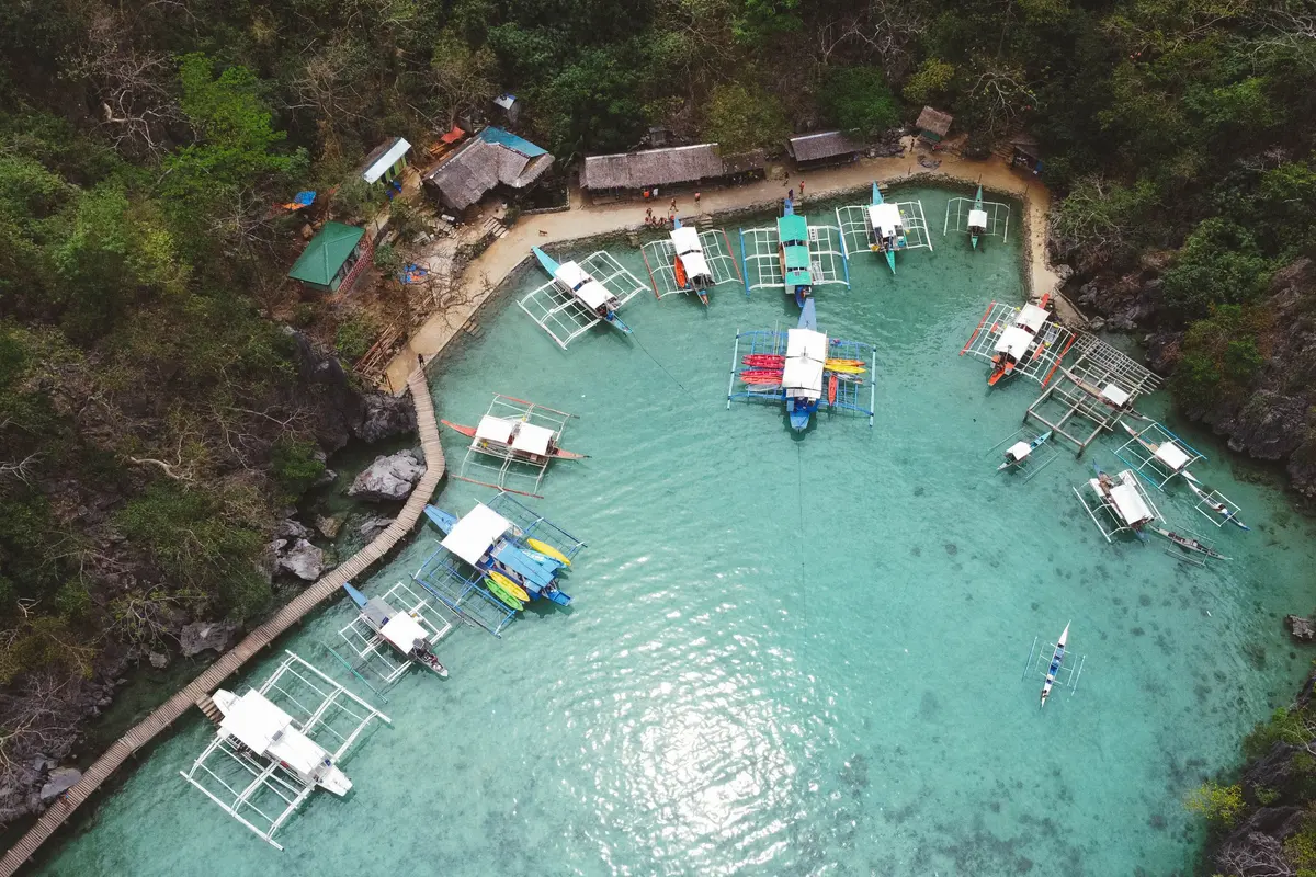 Traditional outrigger boats moored in Coron Bay, Palawan, backed by green limestone cliffs.